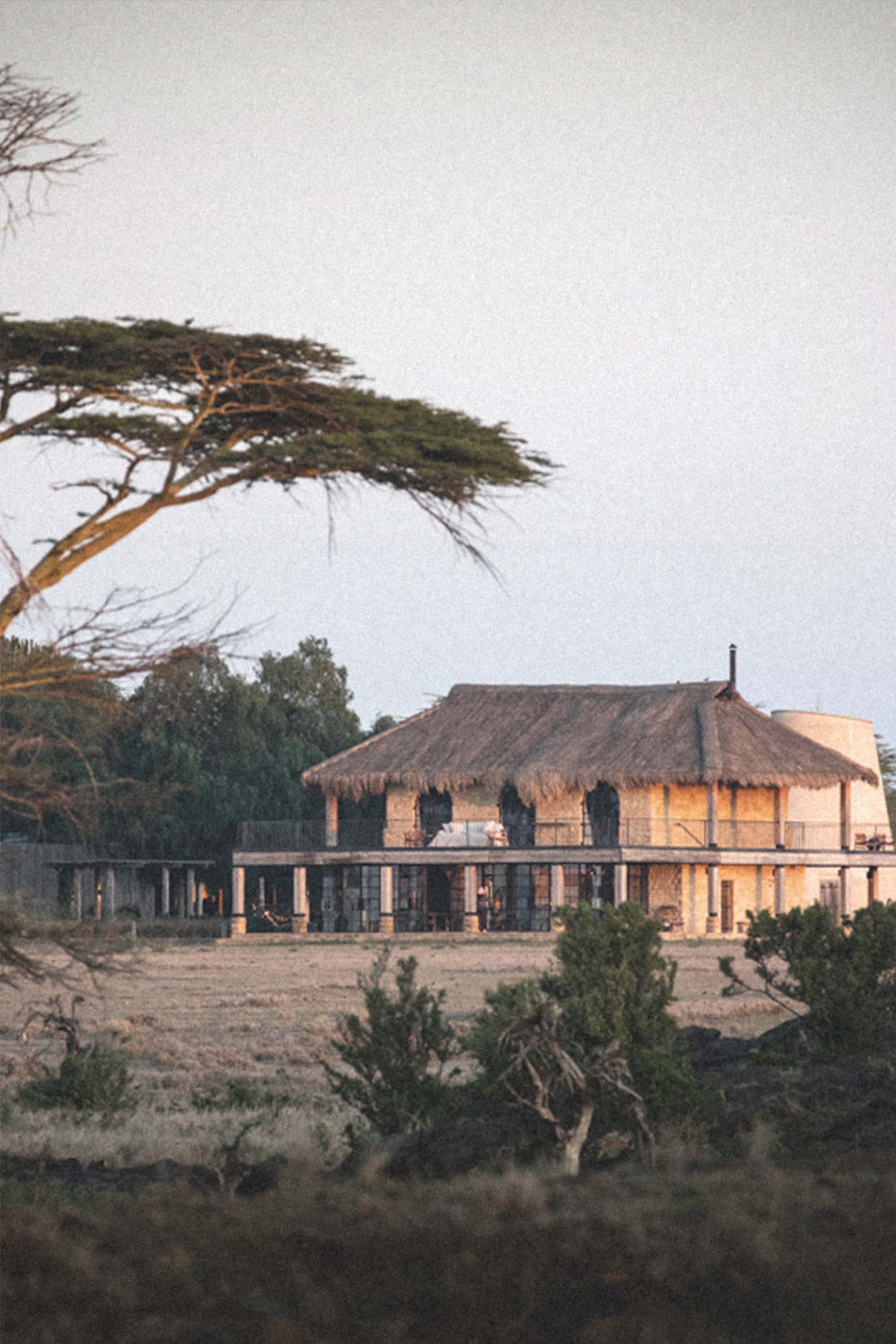 Lodge nestled beneath flat-topped acacia trees in the East African highlands